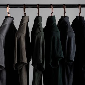 Rack of Grayman and Company pique merino polo shirts on a colour gradient against a gray background with thick luxury hangers