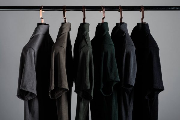 Rack of Grayman and Company pique merino polo shirts on a colour gradient against a gray background with thick luxury hangers