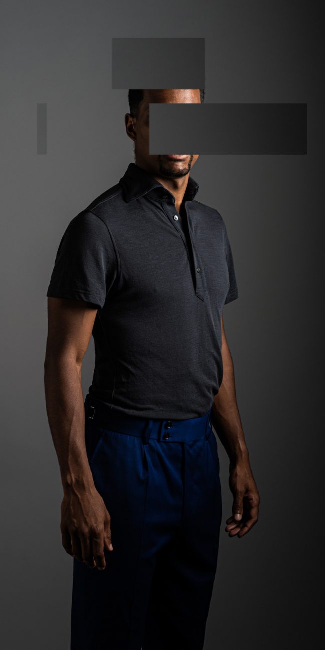 redacted man in studio wearing grey merino pique polo shirt by Grayman and Company with grey backdrop