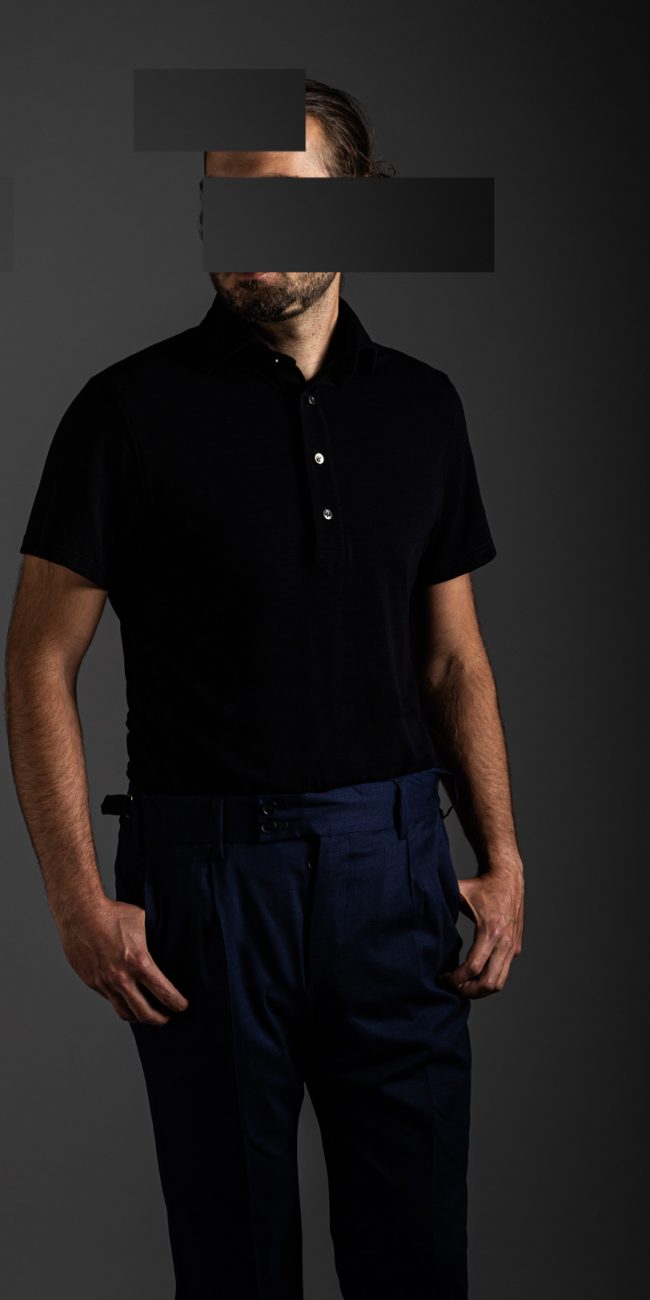 redacted man in studio wearing navy blue merino pique polo shirt by Grayman and Company with grey backdrop