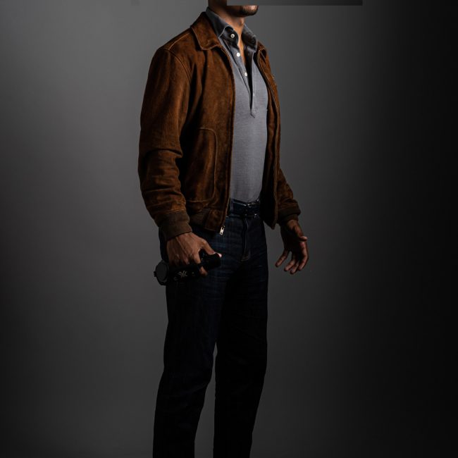 redacted man in studio wearing light grey merino pique polo shirt and suede jacket by Grayman and Company with grey backdrop