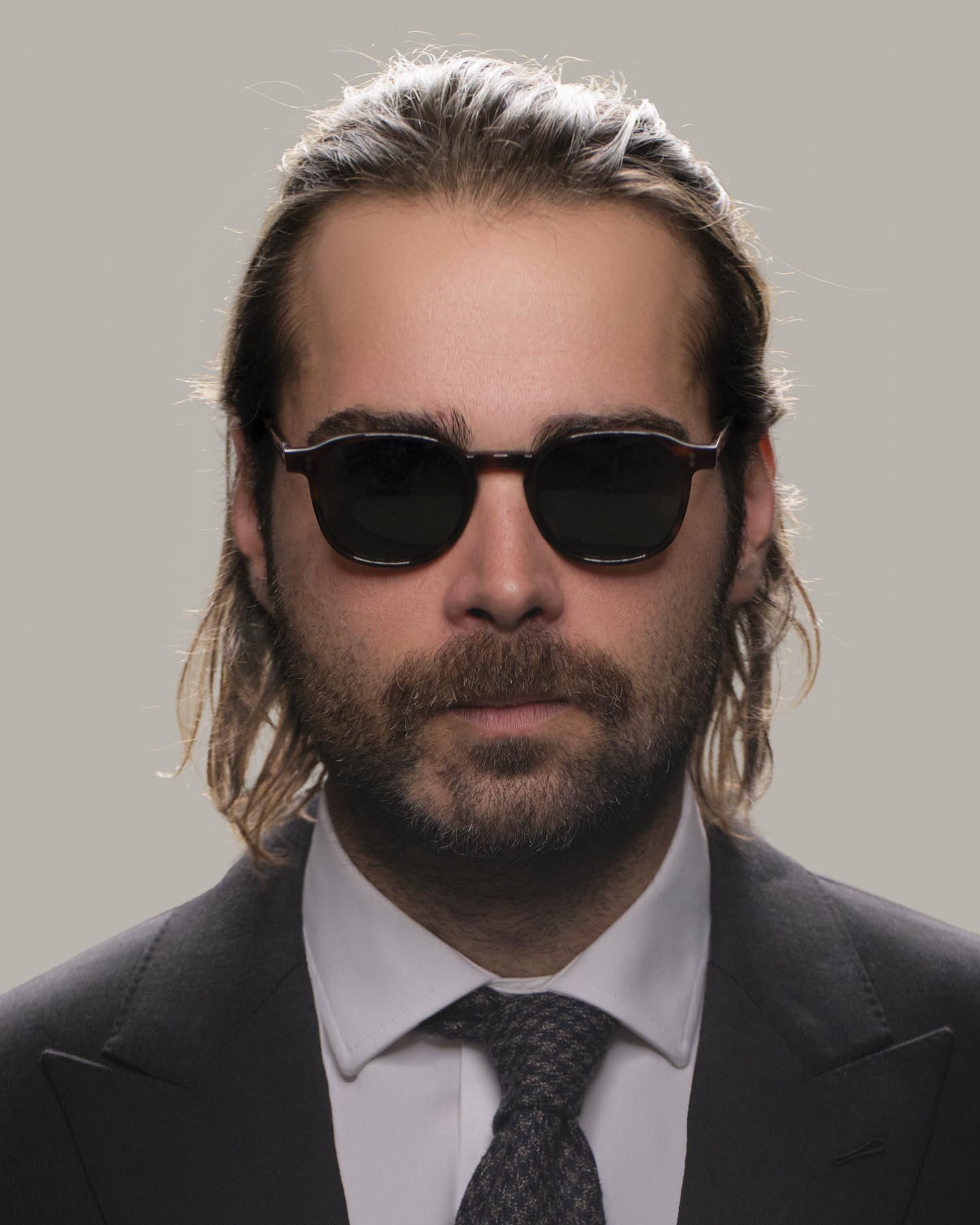 Headshot of man in tactical suit and Grayman and Company KH12 wayfarer ballistic impact resistant sunglasses